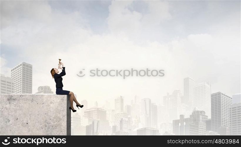 Woman speaking in horn. Young businesswoman sitting on top and proclaiming something in horn