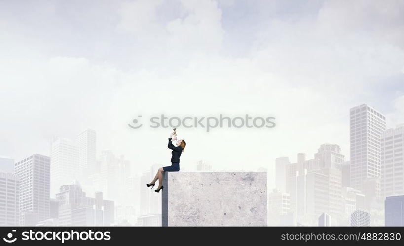 Woman speaking in horn. Young businesswoman sitting on top and proclaiming something in horn