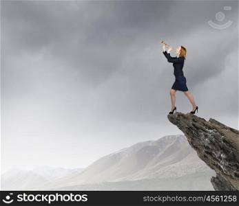 Woman speaking in horn. Young businesswoman standing on rock edge and proclaiming something in horn