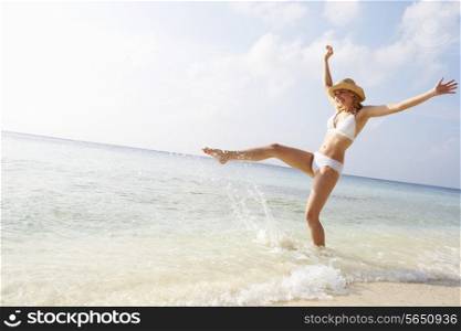 Woman Splashing In Sea On Beach Holiday