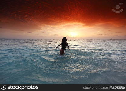 Woman splashing in sea on sunset