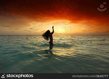 Woman splashing in sea on sunset