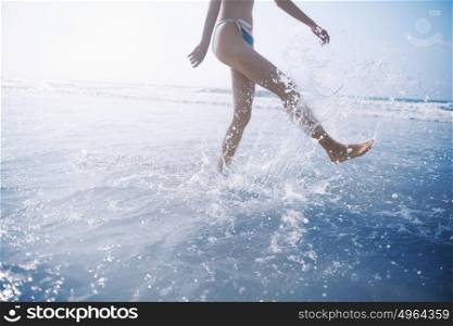 Woman splashing water while walking on beach