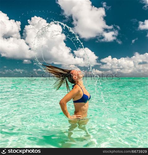 Woman splashing water with hair in the ocean. Woman splashing water with her hair in the ocean