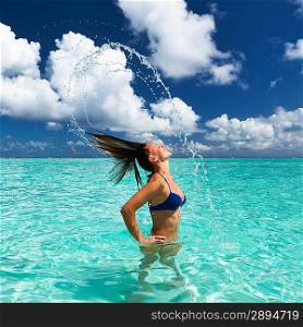 Woman splashing water with her hair in the ocean