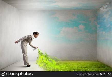 Woman spray grass. Young businesswoman spraying green grass from aerosol balloon