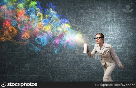 Woman spraying colors. Young businesswoman in glasses using spray balloon