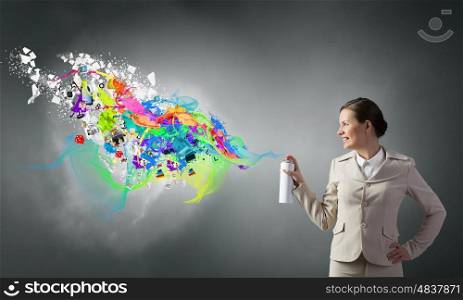 Woman spraying paint. Young businesswoman spraying colorful paint from balloon