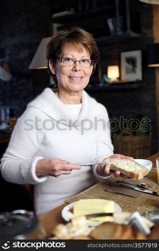Woman spreading butter on a piece of bread