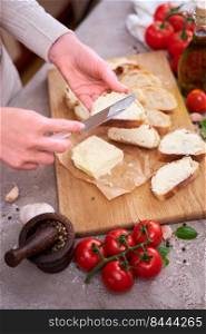 Woman spreading tasty organic butter onto bread over grey table with wooden cutting board.. Woman spreading tasty organic butter onto bread over grey table with wooden cutting board