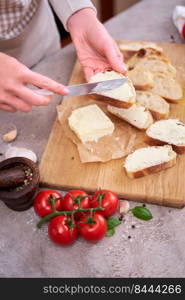 Woman spreading tasty organic butter onto bread over grey table with wooden cutting board.. Woman spreading tasty organic butter onto bread over grey table with wooden cutting board