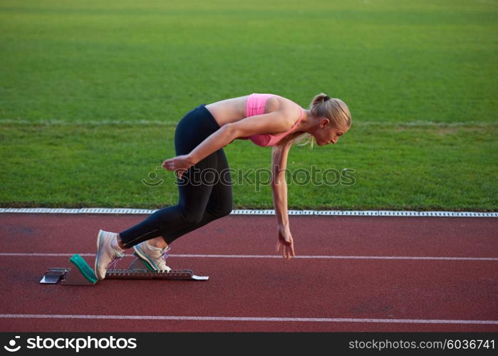 woman sprinter leaving starting blocks on the athletic track. Side view. exploding start