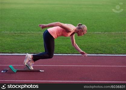 woman sprinter leaving starting blocks on the athletic track. Side view. exploding start