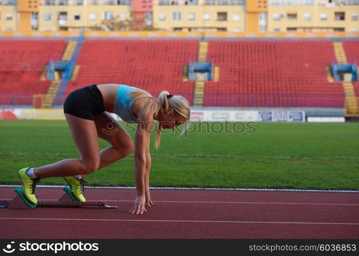 woman sprinter leaving starting blocks on the athletic track. Side view. exploding start