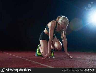 woman sprinter leaving starting blocks on the athletic track. Side view. exploding start