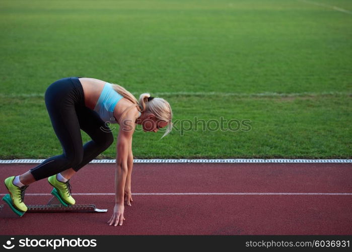 woman sprinter leaving starting blocks on the athletic track. Side view. exploding start