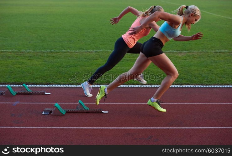 woman sprinter leaving starting blocks on the athletic track. Side view. exploding start