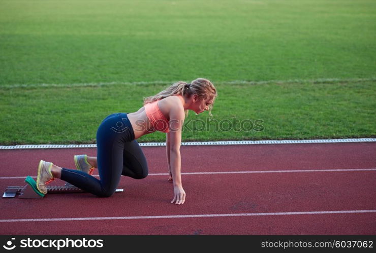 woman sprinter leaving starting blocks on the athletic track. Side view. exploding start