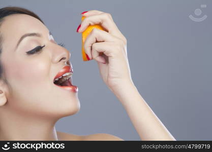 Woman squeezing juice from orange into her mouth