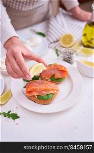 woman squeezing lemon juice on a Cream cheese and Smoked salmon toast.. woman squeezing lemon juice on a Cream cheese and Smoked salmon toast