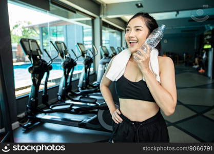 Woman standing and relaxing after exercising, holding a bottle of water to touch the face.