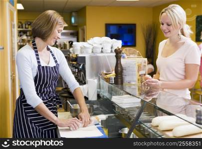 Woman standing at counter in restaurant serving customer smiling