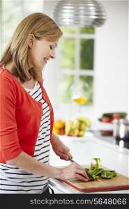 Woman Standing At Counter Preparing Meal In Kitchen