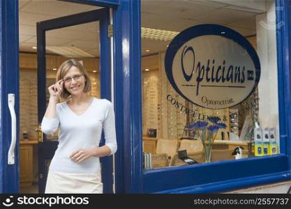 Woman standing at front entrance of optometrists smiling