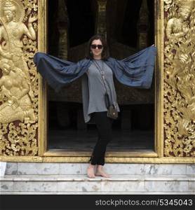 Woman standing at temple, Wat Xieng Thong, Luang Prabang, Laos