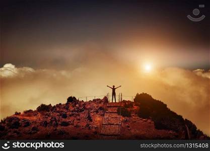 Woman standing back on the mountain peak at sunset, Portugal, Madeira. Woman on the mountain peak