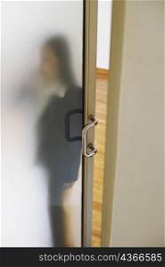 Woman standing behind a door