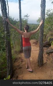 Woman standing between two trees at Mountain Pine Ridge Reserve in Belize