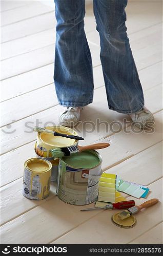 Woman standing by painting materials on floor