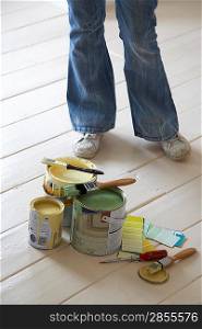 Woman standing by painting materials on floor