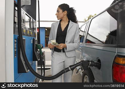 Woman standing by van with fuel pump counting money
