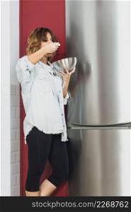 woman standing eating near fridge