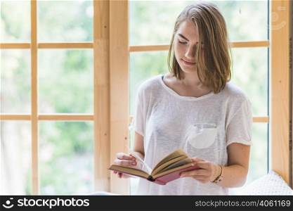 woman standing front window reading book