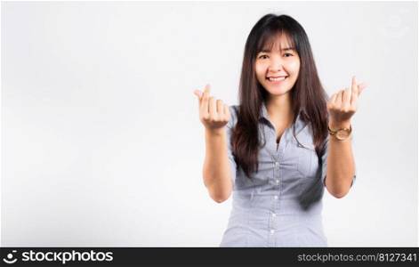 Woman standing her smile confidence showing mini heart sign with her finger isolated white background, Asian happy portrait beautiful young female send love and happy valentine in studio shot