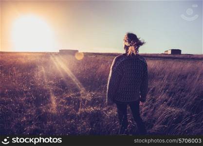 Woman standing in a field at sunset