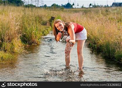 Woman standing in a little creek with her ankles in the water, the cold water is refreshing in the summer heat