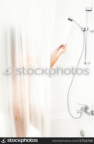 Woman standing in bath behind curtain and having shower