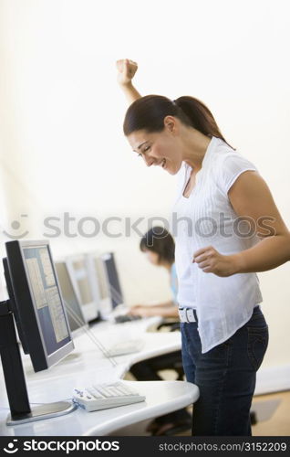 Woman standing in computer room cheering and smiling