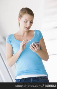 Woman standing in corridor using personal digital assistant