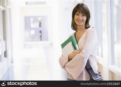 Woman standing in corridor with books (high key)