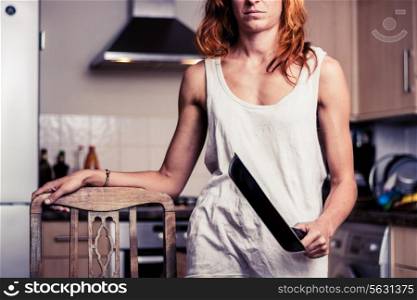 Woman standing in kitchen with a frying pan