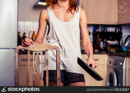 Woman standing in kitchen with a frying pan