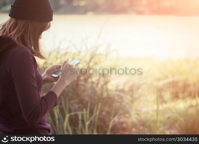 Woman standing in park writing text on smartphone