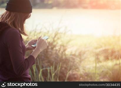 Woman standing in park writing text on smartphone