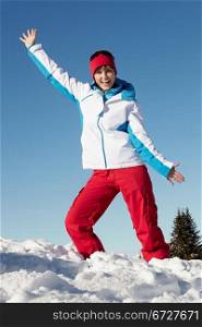 Woman Standing In Snow Wearing Warm Clothes On Ski Holiday In Mountains