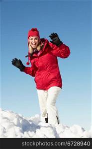Woman Standing In Snow Wearing Warm Clothes On Ski Holiday In Mountains